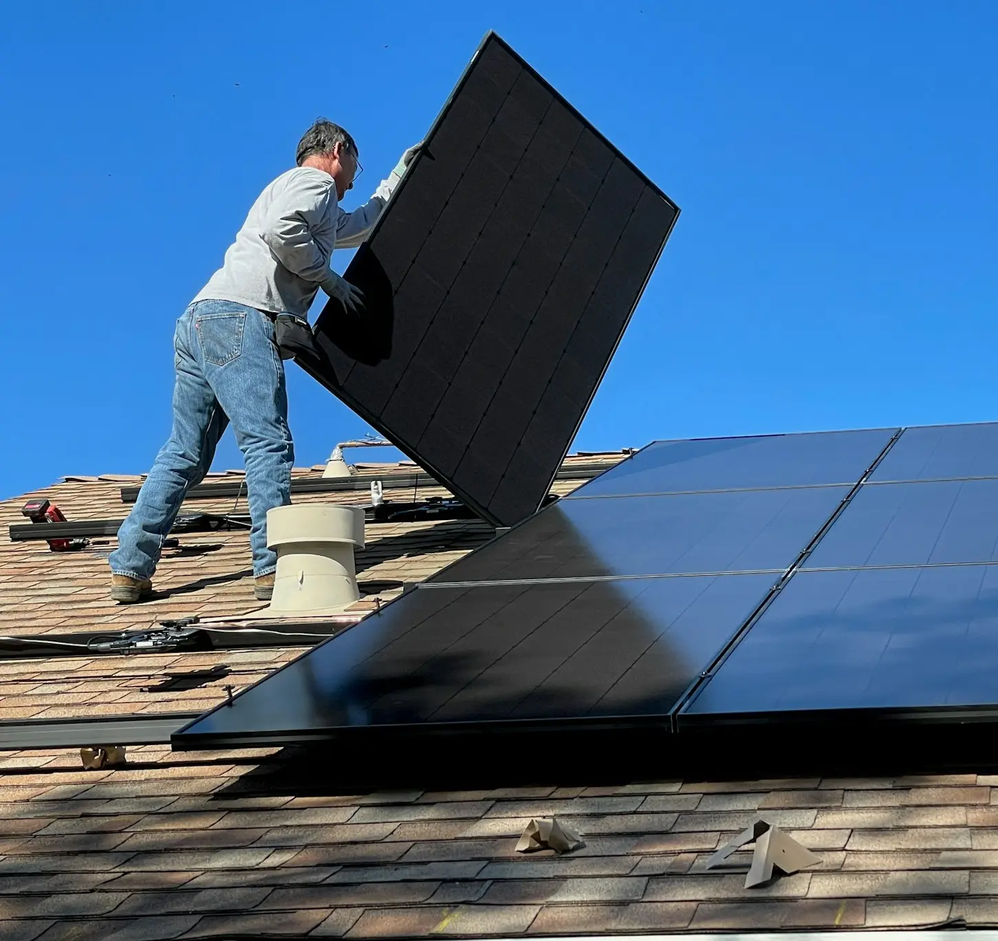 man in white dress shirt and blue denim jeans sitting on white and black solar panel